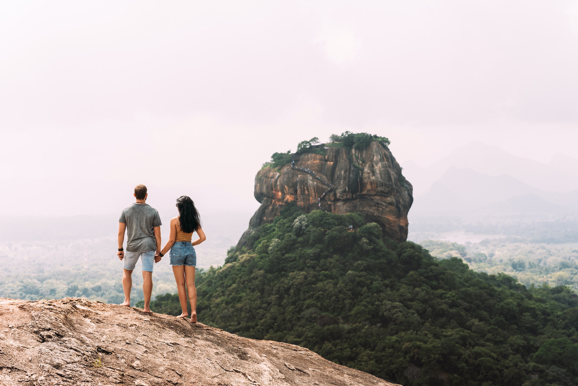 A couple in love on a rock admires the beautiful views. A couple in love travels