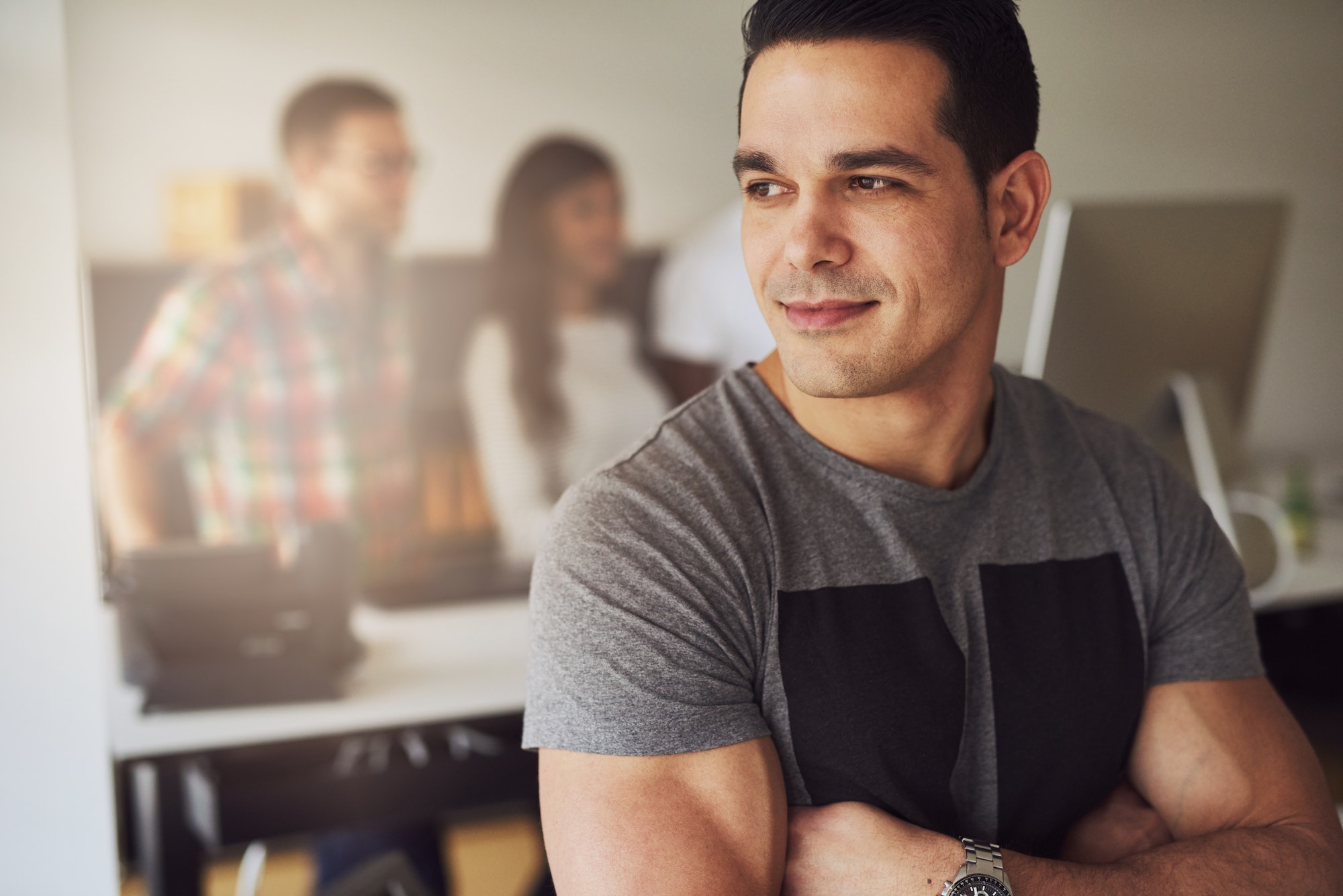 Calm muscular man in office with co-workers